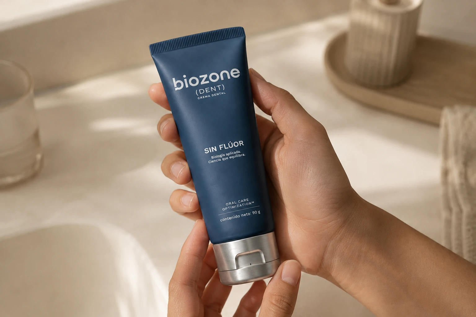 Manos sosteniendo el tubo de Biozone Dent sobre una mesada clara, con luz de la mañana